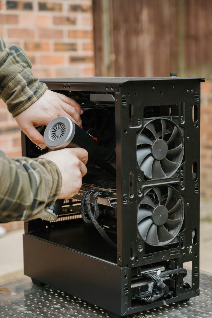 pexels-photo-31854227-31854227 Hands cleaning a desktop PC case with an electric duster outdoors.