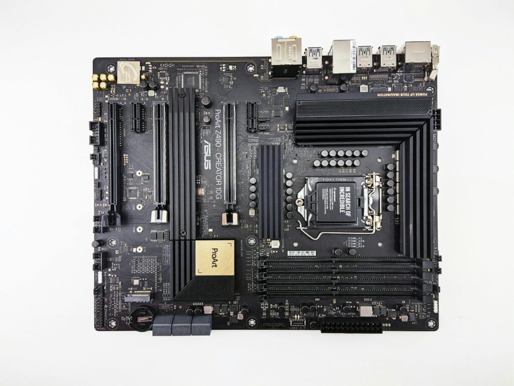 pexels-photo-5553597-5553597 Flat lay image showcasing an ASUS Z490 motherboard with its components on a white background.