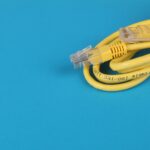Close-up of a yellow Ethernet cable with connectors on a blue background.