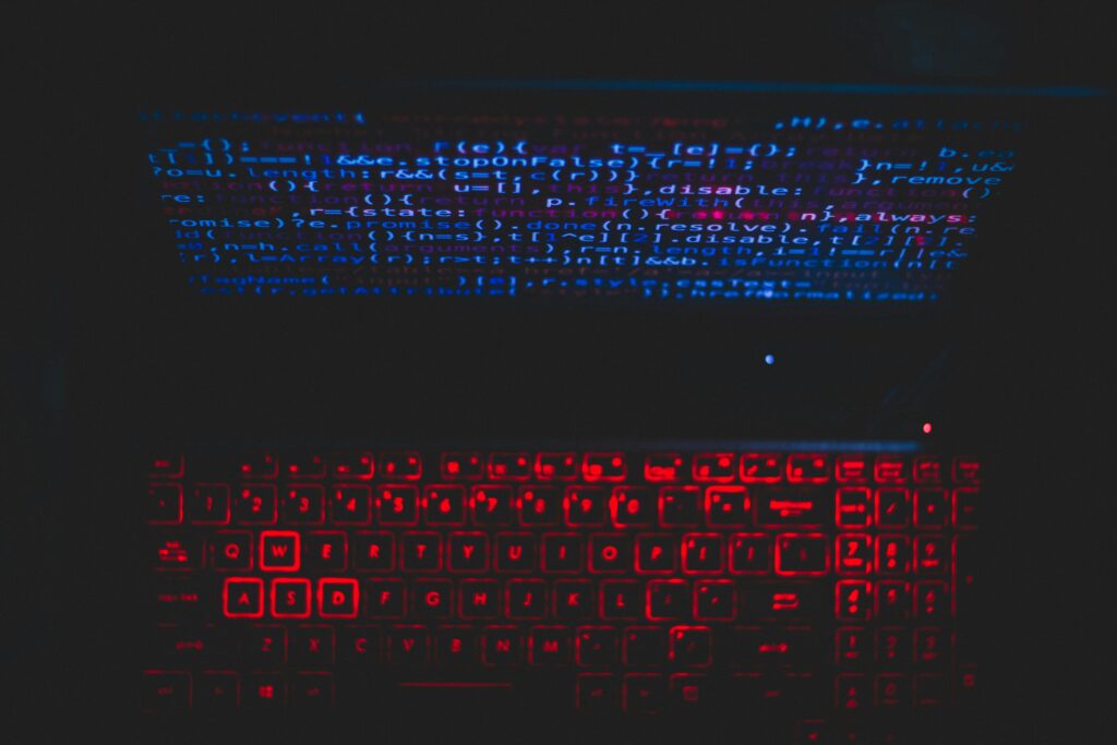pexels-photo-1933900-1933900 Dark-themed laptop setup with a red glowing keyboard and code on screen, ideal for tech enthusiasts.